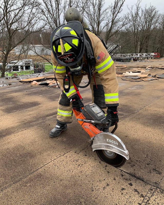 firefighter using tool to cut into pavement